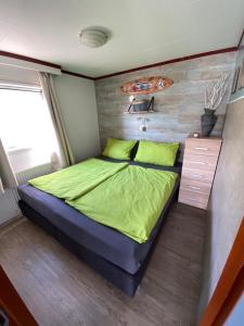 a bedroom with a large bed with green sheets at Beachhouses Texel in De Koog