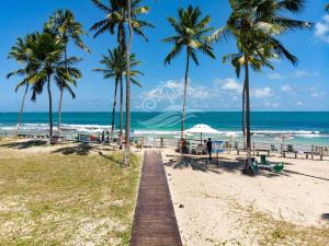 a boardwalk on a beach with palm trees and the ocean at Flat Carneiros in Tamandaré