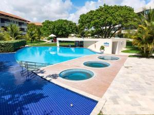 a large swimming pool with blue tiles in a yard at Flat Carneiros in Tamandaré