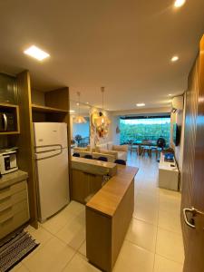 a kitchen with a refrigerator and a living room at Flat Carneiros in Tamandaré