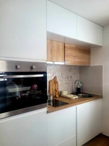 una cocina con armarios blancos y fregadero en Zlatna Jabuka apartman en Prijepolje