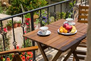 un tavolo di legno con due tazze di tè e frutta sopra di Sokaki House a Kalivianí