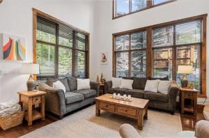 a living room with couches and tables and windows at Pinnacle Ridge Luxury Condo 2 in Whitefish