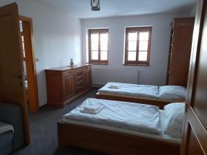 a bedroom with two beds and a dresser and two windows at Koliba Holica in Huty