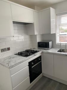 een witte keuken met een fornuis en een magnetron bij Adsa Guesthouse in Seacroft