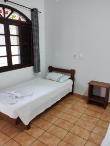 Schlafzimmer mit einem Bett, einem Fenster und einem Tisch in der Unterkunft Hotel Xaréu in Ubatuba