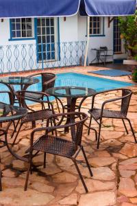 a glass table and chairs next to a swimming pool at Pousada Villa Real in Sabará