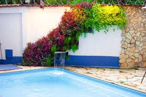 a swimming pool in front of a building with flowers at Pousada Villa Real in Sabará