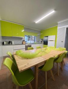 uma cozinha com uma mesa de madeira e cadeiras verdes em Cantinho Verde T3 no Gerês