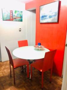 a table with chairs and a white table and red wall at Lovely Depa. Forosol Palacio Airport 10 Min in Mexico City