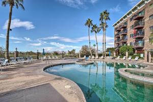 a pool with chairs and palm trees in front of a building at Resort-Style Lake Havasu City Condo with Pool! in Lake Havasu City
