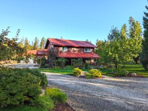ein Haus mit rotem Dach auf einer Schotterstraße in der Unterkunft Tall Timbers Cabin in West Glacier
