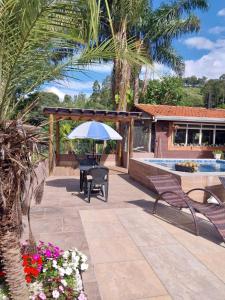 a patio with a table and an umbrella and flowers at Pousada Beija flor in Extrema