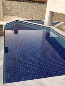 una piscina con suelo de baldosa azul en Flat com varanda beira-mar, en João Pessoa