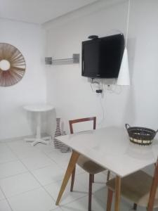 sala de estar con mesa y TV en la pared en Flat com varanda beira-mar, en João Pessoa