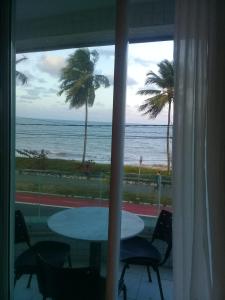 una ventana con vistas al océano, mesa y sillas en Flat com varanda beira-mar, en João Pessoa