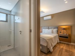 a bedroom with a bed and a walk in shower at Allure 102 - Apto em Gramado Av das Hortênsias in Gramado