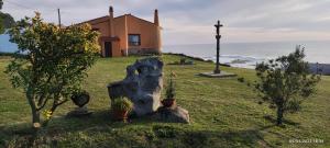 a house with a statue of a rock in the grass at A Guaira: fantástica alojamiento con finca sobre el mar in Oia