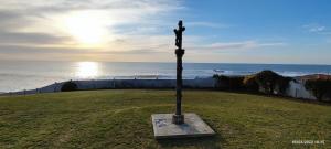 a statue of a cross in the grass near the ocean at A Guaira: fantástica alojamiento con finca sobre el mar in Oia