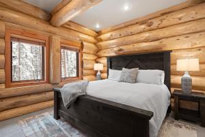 a bedroom with a bed and wooden walls and windows at The Grand Alpine Lodge in Whitefish
