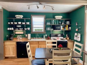 una cucina con pareti verdi e tavolo e sedie di Walker's Place a Outback Mobile Home Settlement