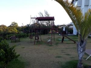 um parque infantil com um baloiço num quintal em Apartamento pé na areia em frente a Ilha do Campeche em Florianópolis