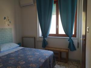 ミントゥルノにあるCamere "Riviera di Ulisse"のベッドルーム1室(ベッド1台、青いカーテン付きの窓付)