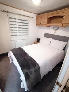 a bedroom with a large white bed and a window at Cornwall CORNWALL-CHAPMANSWELL CARAVAN HOLIDAY PARK A30 B&B Bed and breakfast #41 in Launceston