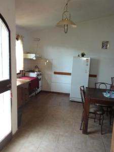 uma cozinha com uma mesa e um frigorífico branco em Lago Azul em Embalse