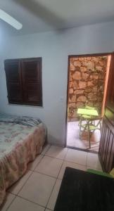 a bedroom with a bed and a table and a window at Suites Solar dos Arcanjos Guaramiranga in Guaramiranga