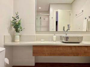 a bathroom with a sink and a mirror at Apartamento Villaggio Del Veneto 1 dorm by Achei in Canela +33 photos