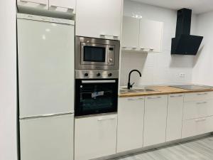 a kitchen with white cabinets and a microwave at Estadio playa in Almería