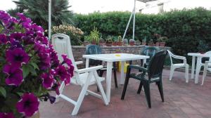 een patio met tafels en stoelen en paarse bloemen bij Camere "Riviera di Ulisse" in Minturno