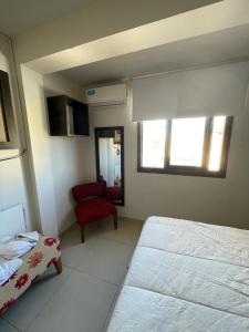1 dormitorio con 1 cama y 1 silla roja en Federal 498 en La Rioja