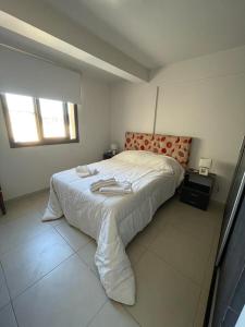 Un dormitorio blanco con una cama con toallas. en Federal 498 en La Rioja