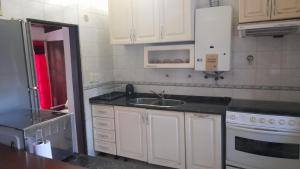 una cocina con armarios blancos y fregadero en Departamento Los Nogales I en San Fernando del Valle de Catamarca