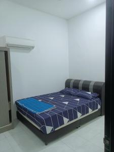 a bed with a blue comforter in a room at Homestay baitijannati in Pasir Mas