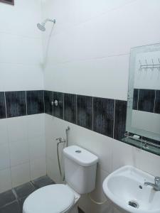 La salle de bains est pourvue de toilettes, d'un lavabo et d'un miroir. dans l'établissement Homestay baitijannati, à Pasir Mas