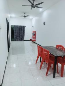 a dining room with a table and red chairs at Homestay baitijannati in Pasir Mas