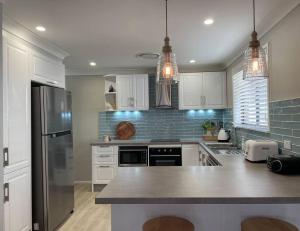 a kitchen with white cabinets and a stainless steel refrigerator at 'Anchor Management' Recently Renovated 3BR / 2BTH in Nelson Bay