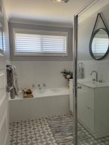 a white bathroom with a tub and a sink at 'Anchor Management' Recently Renovated 3BR / 2BTH in Nelson Bay