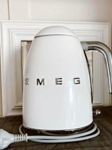 a white tea kettle with a brush on a counter at The little cottage in Tauranga