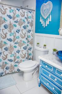 a bathroom with a toilet and a blue shower curtain at Miami Boho Beach Place in Hialeah