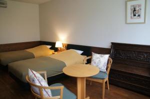 富良野市にあるフィトンチッド森の香りのベッド2台、テーブルと椅子が備わるホテルルームです。