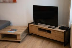 sala de estar con TV de pantalla plana en un centro de entretenimiento de madera en La Maison aux Coquelicots, en Flers