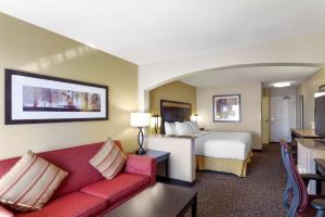 a hotel room with a bed and a red couch at Best Western Plus Castle Rock in Castle Rock
