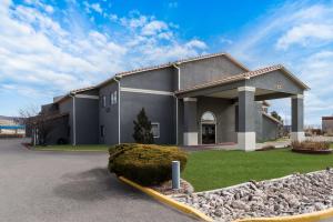 a large gray building with a stone wall at SureStay Hotel by Best Western Grants in Grants