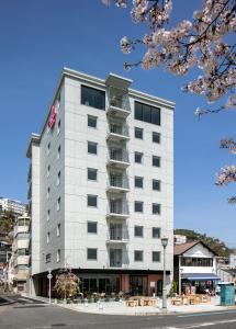 un edificio blanco alto en una calle de la ciudad en Sakura Hotel Onomichi Ekimae, en Onomichi