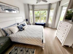 a bedroom with a bed and a dresser and windows at GreenLinks Golf View Villa Flamingo at Lely Resort in Naples