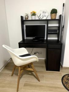 uma cadeira branca em frente a uma secretária com uma televisão em Artistic Digital Getaway - Patio & GREAT Location! em Lisboa
